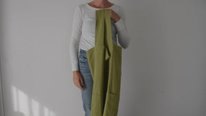 woman showing how to wear the organic cross-back Japanese smock apron in chartreuse green linen by portland apron company. 